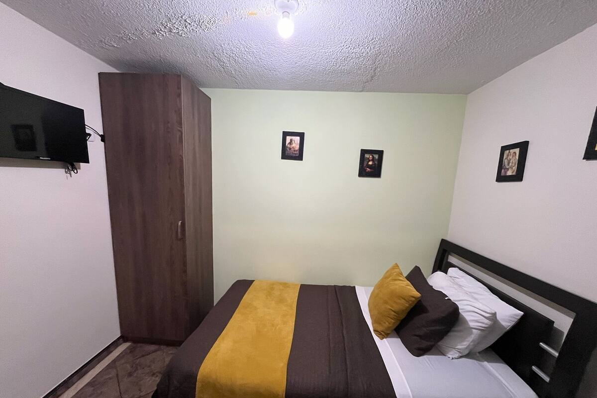 Een slaapkamer met een bed, een kledingkast en een wandgemonteerde flatscreen-televisie.