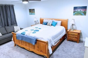 Una camera da letto con un letto in legno, un divano grigio e un comodino con una lampada.