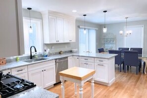 A modern kitchen with white cabinetry, a wooden island, and pendant lighting. - Whispering Pines: Nearby Kingston Lake | Monthly (Kingston)