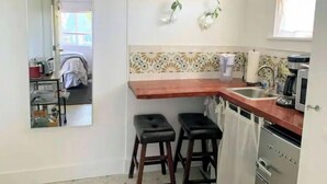 Une cuisine compacte avec un plan de travail en bois, deux tabourets, un évier et une machine à café.