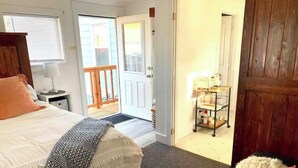 Une chambre à coucher avec un lit, une table de chevet, une porte en bois et une vue sur l’extérieur.