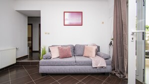 A modern living room with a grey sofa, a red-framed picture on the wall, and a glass door with curtains. - Apartments Alisa - Two Bedroom Apartment with Terrace and Sea View (novi) (Brodarica)