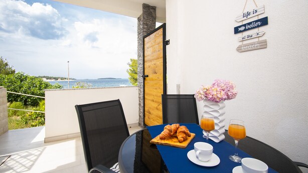 A breakfast table with croissants, orange juice, and coffee cups, overlooking a scenic view. - Apartments Alisa - Two Bedroom Apartment with Terrace and Sea View (novi) (Brodarica)