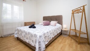 A bedroom with a bed, bedside table, lamp, and a wooden drying rack. - Apartments Alisa - Two Bedroom Apartment with Terrace and Sea View (novi) (Brodarica)