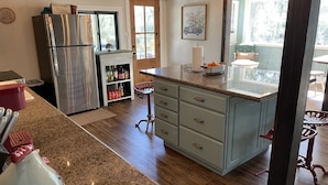 Una cocina con refrigerador de acero inoxidable, horno empotrado, encimera de granito y piso de madera.