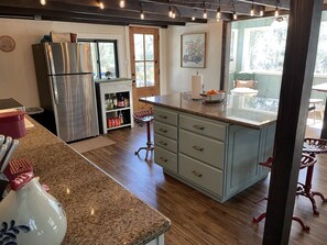 Una cocina con refrigerador de acero inoxidable, horno empotrado, encimera de granito y piso de madera.
