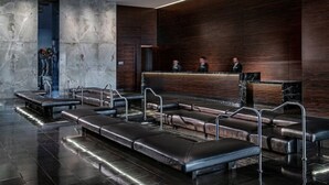 Un área de recepción moderna con un mostrador de madera oscura, asientos de cuero y una pared de mármol.