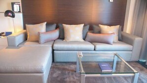 Una sala moderna con un conjunto de sofás, una mesa de centro de vidrio y una lámpara.