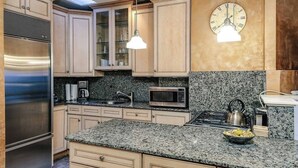 Una cucina con piani di lavoro in granito, elettrodomestici in acciaio inossidabile e mobili in legno chiaro.