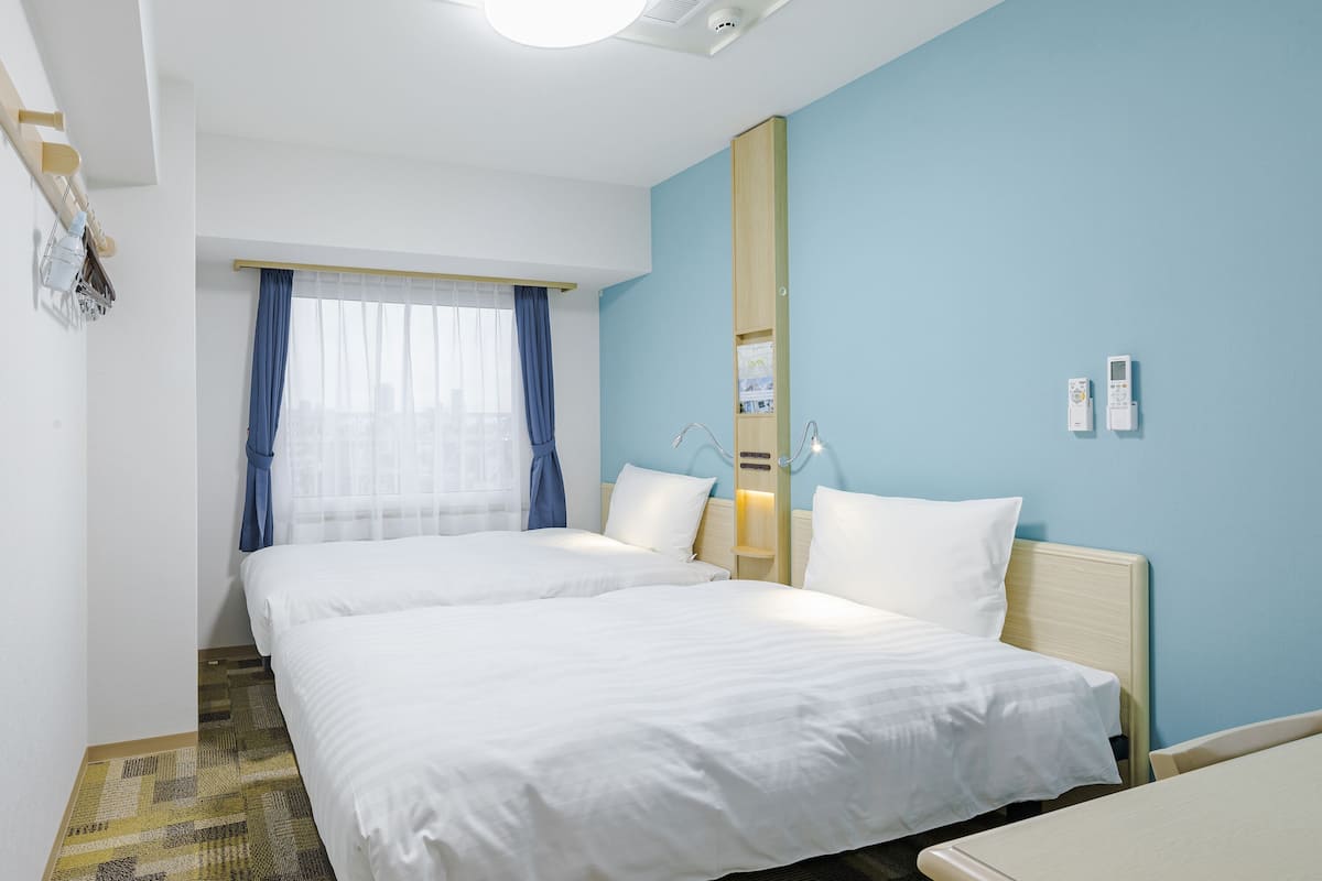 Ein Hotelzimmer mit zwei Betten, einem großen Spiegel, einem Nachttisch und einer Deckenleuchte.