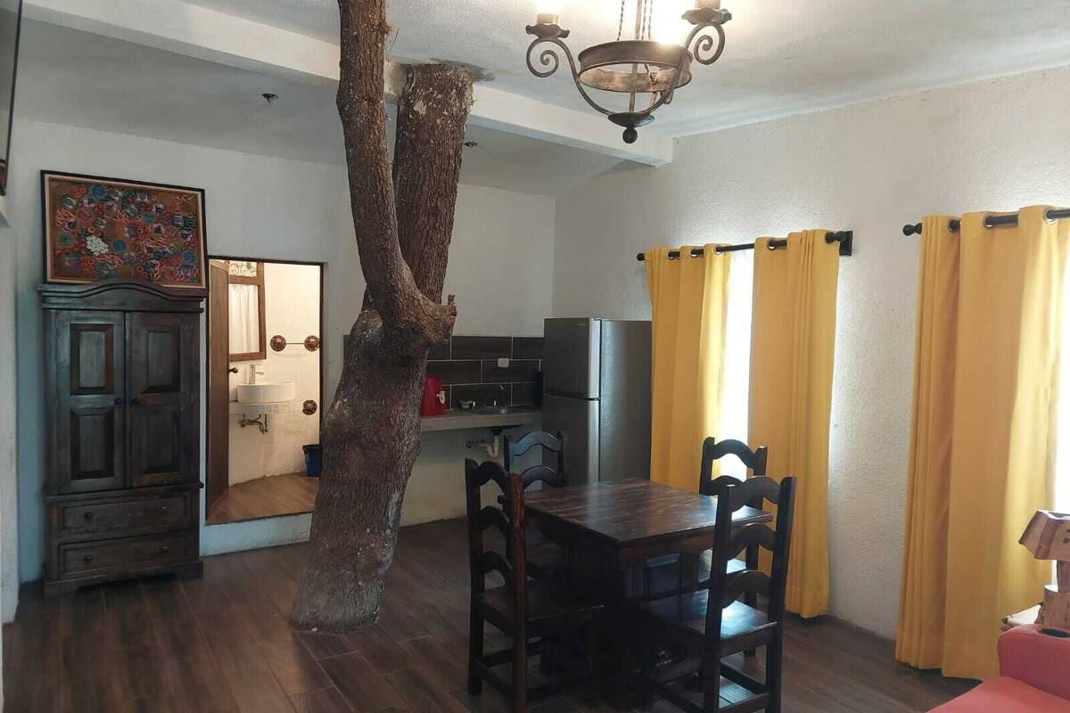 A dining area with a wooden table and chairs, a chandelier, and yellow curtains.