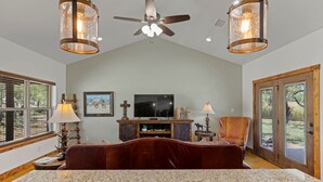 A spacious living room with a large bed, a television, and a fireplace.
