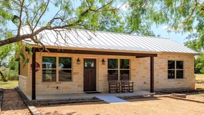 A small stone building with a metal roof, a front door, and two windows.