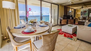 A dining area with a table set for four, a sofa, and a television in a living room. - Hawaiian Princess at Makaha Beach (Waianae)