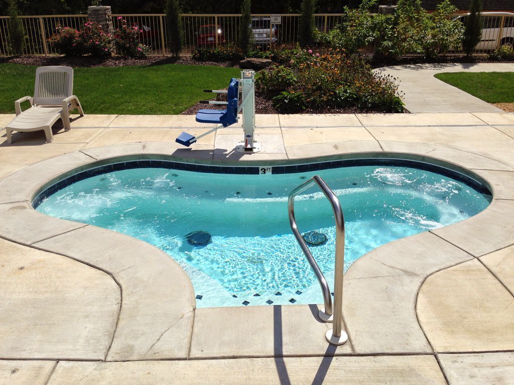 A swimming pool with a ladder, surrounded by a tiled deck.