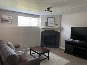 A living room with a fireplace, a sofa, a coffee table, and a television.
