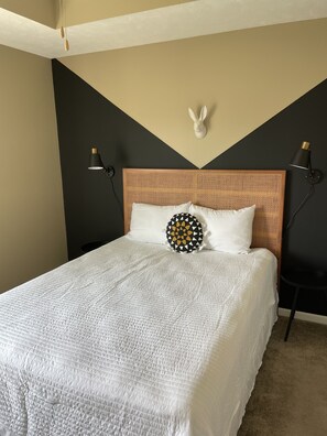 Cozy retreat with a central bed, flanked by nightstands and a geometric wall design.