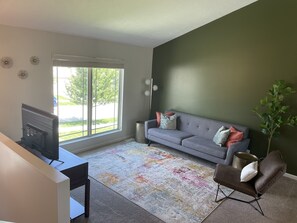 Relax in this stylish living room with a sofa, armchair, and TV, offering a view of the outdoors.