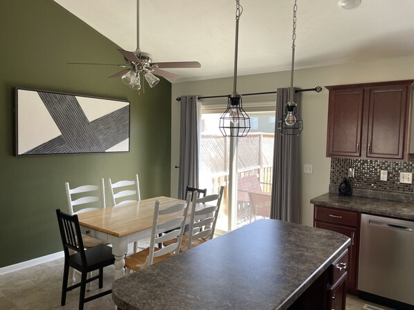 Enjoy meals in the spacious kitchen with a large island, stainless steel appliances, and a dining area with a wooden table and sliding glass door to the backyard.