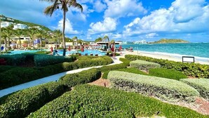 A resort with a pool area, palm trees, and a view of the ocean. - Dawn Beach Club Villa. With Beach access.  (Philipsburg)