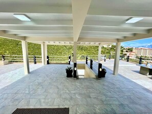 Relax on a spacious covered terrace with a modern design, surrounded by lush greenery and a distant view.
