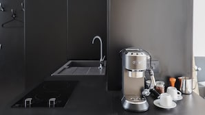 Una cocina moderna con cafetera espresso integrada, un lavamanos y una hornalla.