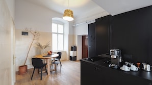 Una cocina moderna con encimera negra, cafetera y zona de comedor con mesa redonda y sillas.