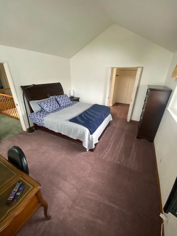 A bedroom with a bed, bedside table, lamp, and a desk with a remote control. - Spacious Sequoia Estate (Eureka)