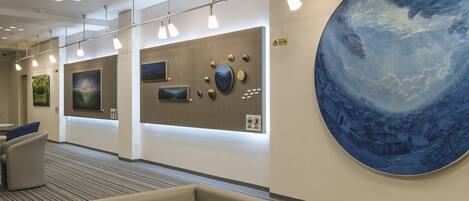 A modern lobby with a large blue mural, recessed lighting, and a seating area.