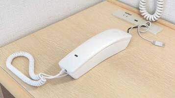Teléfono blanco con un cable enrollado sobre una mesa de madera.