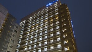 A multi-story hotel with a uniform facade, numerous balconies, and a prominent signage at the top.