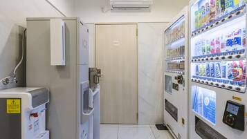 A hotel bathroom with a shower, a private door, a water dispenser, and a vending machine.