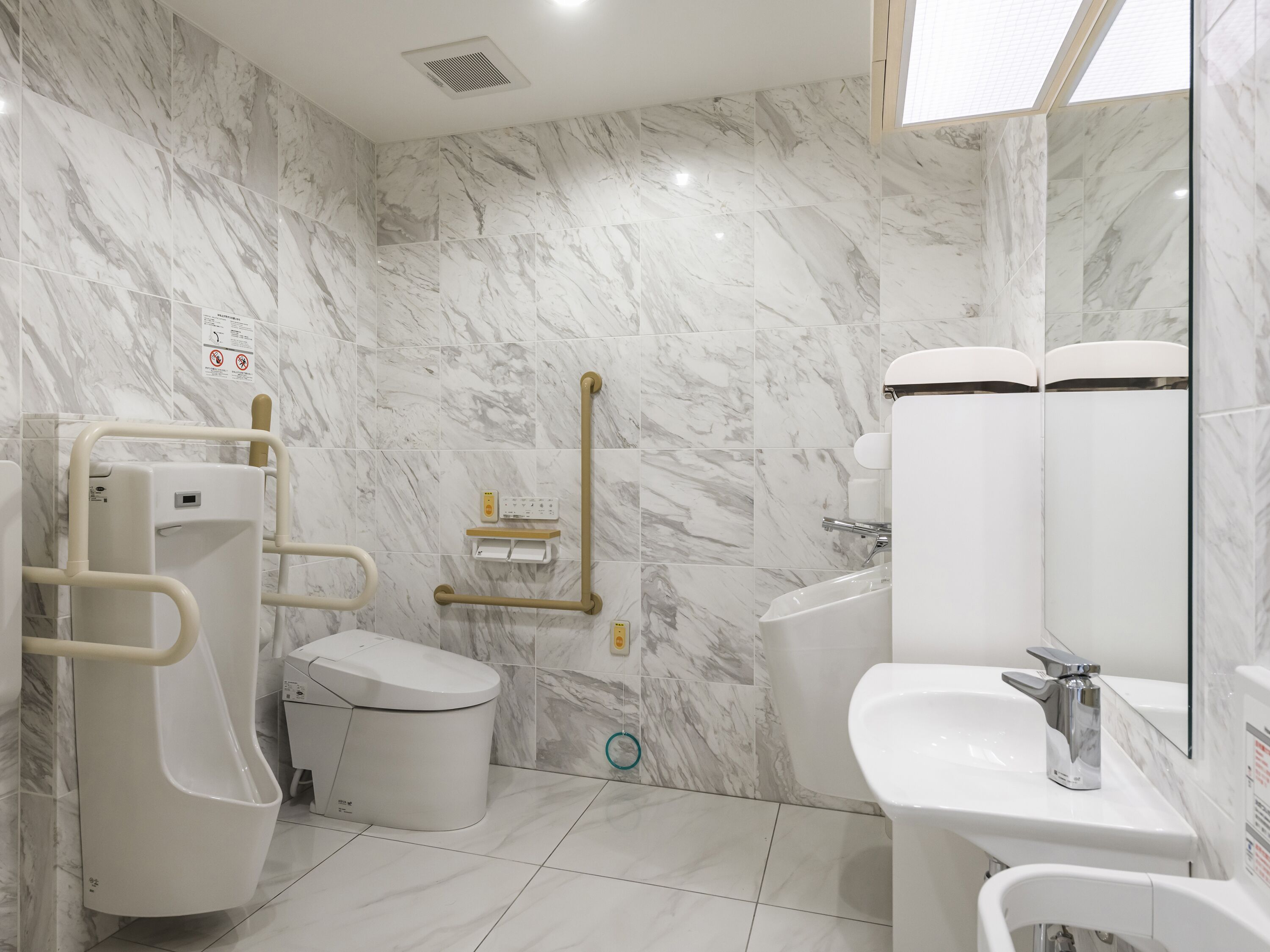 Un baño moderno con paredes de mármol, un inodoro, un bidé y un lavamanos.