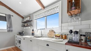 A modern kitchen with white cabinetry, a wooden countertop, a built-in oven, and a window with a view. - Wakefields - an enchanting mountain view cottage (Mole Creek)
