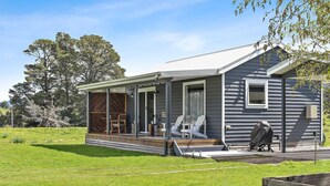 A single-story house with a covered porch, a barbecue grill, and a small deck. - Wakefields - an enchanting mountain view cottage (Mole Creek)
