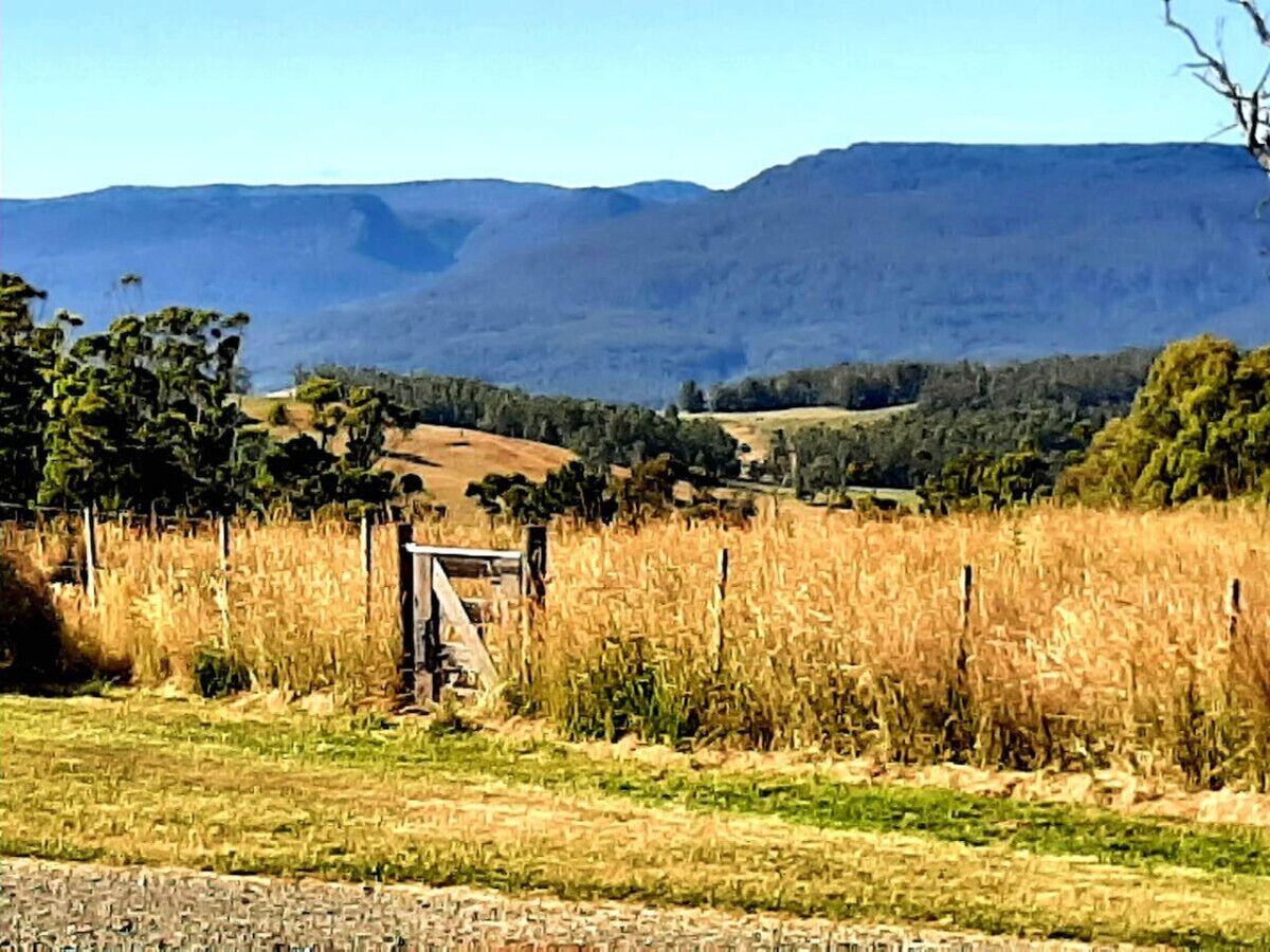 Un paisaje rural con una cerca, campos y montañas a lo lejos.