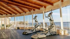 Une salle de sport équipée de vélos d’appartement, dotée de grandes fenêtres et d’un plafond en bois.