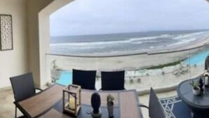 Un balcon avec vue sur l’océan, aménagé avec une table, des chaises et un canapé.