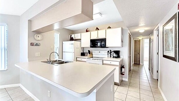 A modern kitchen with a central island, white cabinetry, a microwave, and a stove. - Potter/Jedi vacation villa- Disney Parks 5 miles (Kissimmee)