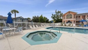 A swimming pool area with lounge chairs and umbrellas, surrounded by a white fence. - Potter/Jedi vacation villa- Disney Parks 5 miles (Kissimmee)