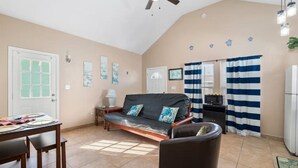 A cozy living room with a sofa, a dining table, and a ceiling fan.