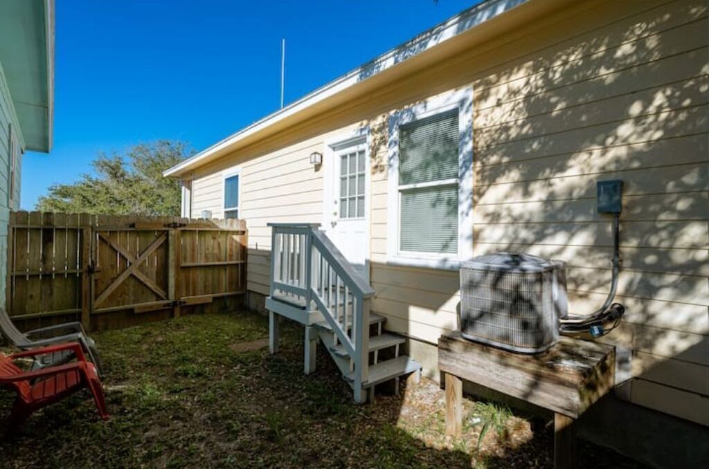 A residential property with a wooden deck, a covered outdoor seating area, and a small staircase leading to a porch.