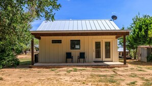 A single-story building with a covered porch, two windows, and a door.