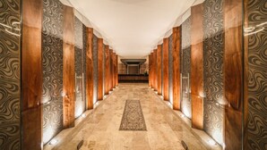 Un pasillo con paredes estampadas y una alfombra central, que conduce a una habitación con techo decorado.