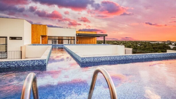 Un edificio moderno con piscina y vistas al atardecer.