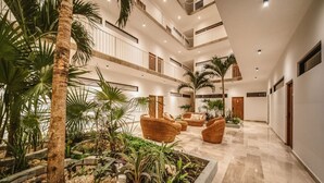 Un atrio de varios niveles con un jardín central, mobiliario de mimbre y un suelo pulido.