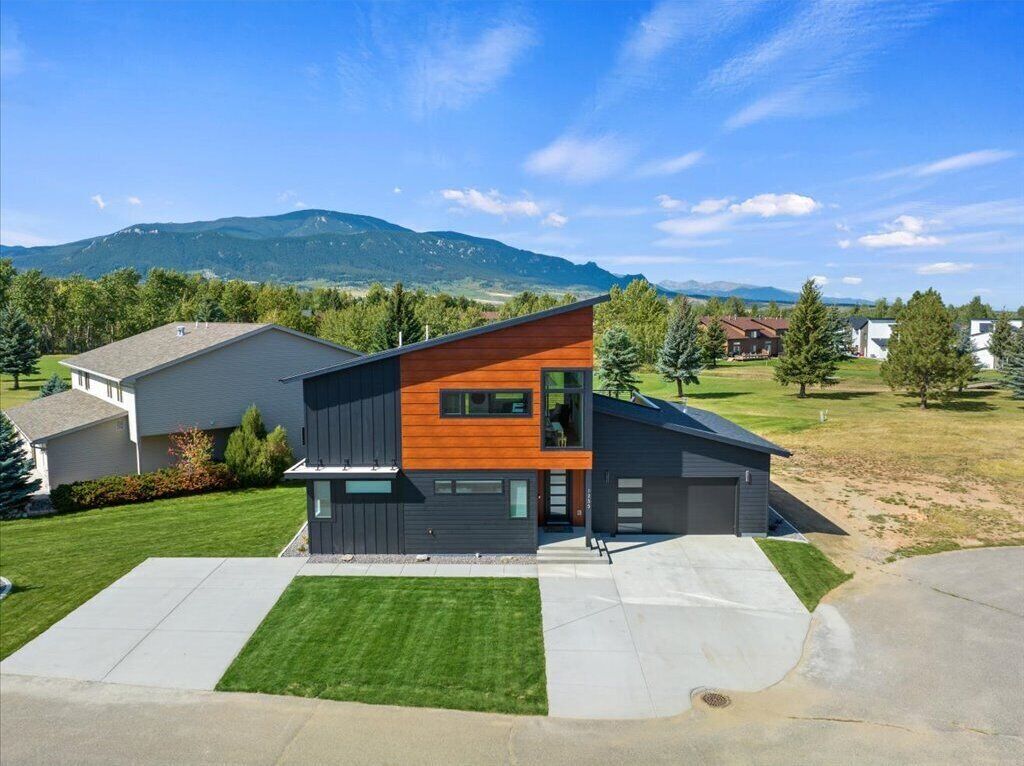 A modern two-story house with a flat roof, a large garage, and a well-maintained lawn.