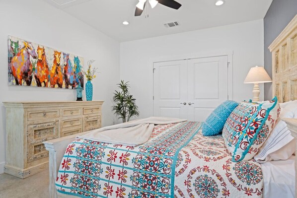A bedroom with a bed, a dresser, a door, and a painting on the wall.