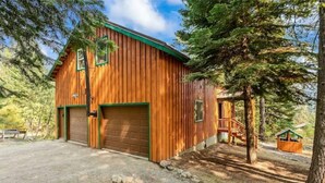 Eine Holzhütte mit Garage, überdachter Veranda und kleinem Geräteschuppen.