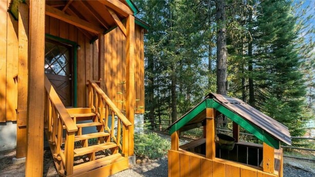 Eine Holzhütte mit Veranda und einem kleinen Hundehäuschen.